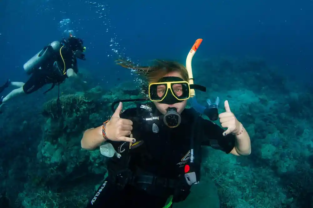 A diver giving two thumbs up in clear blue water