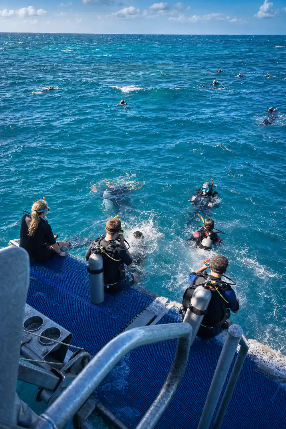 Divers entering the water in sequence from the blue platform