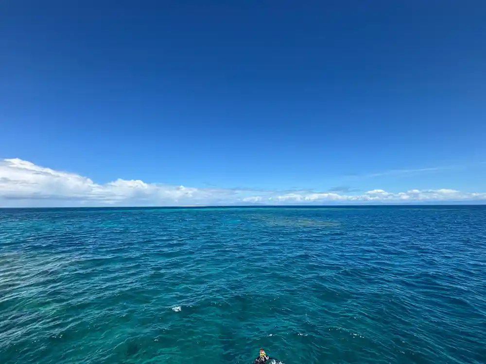 Flat blue water and a low cloud line at the reef