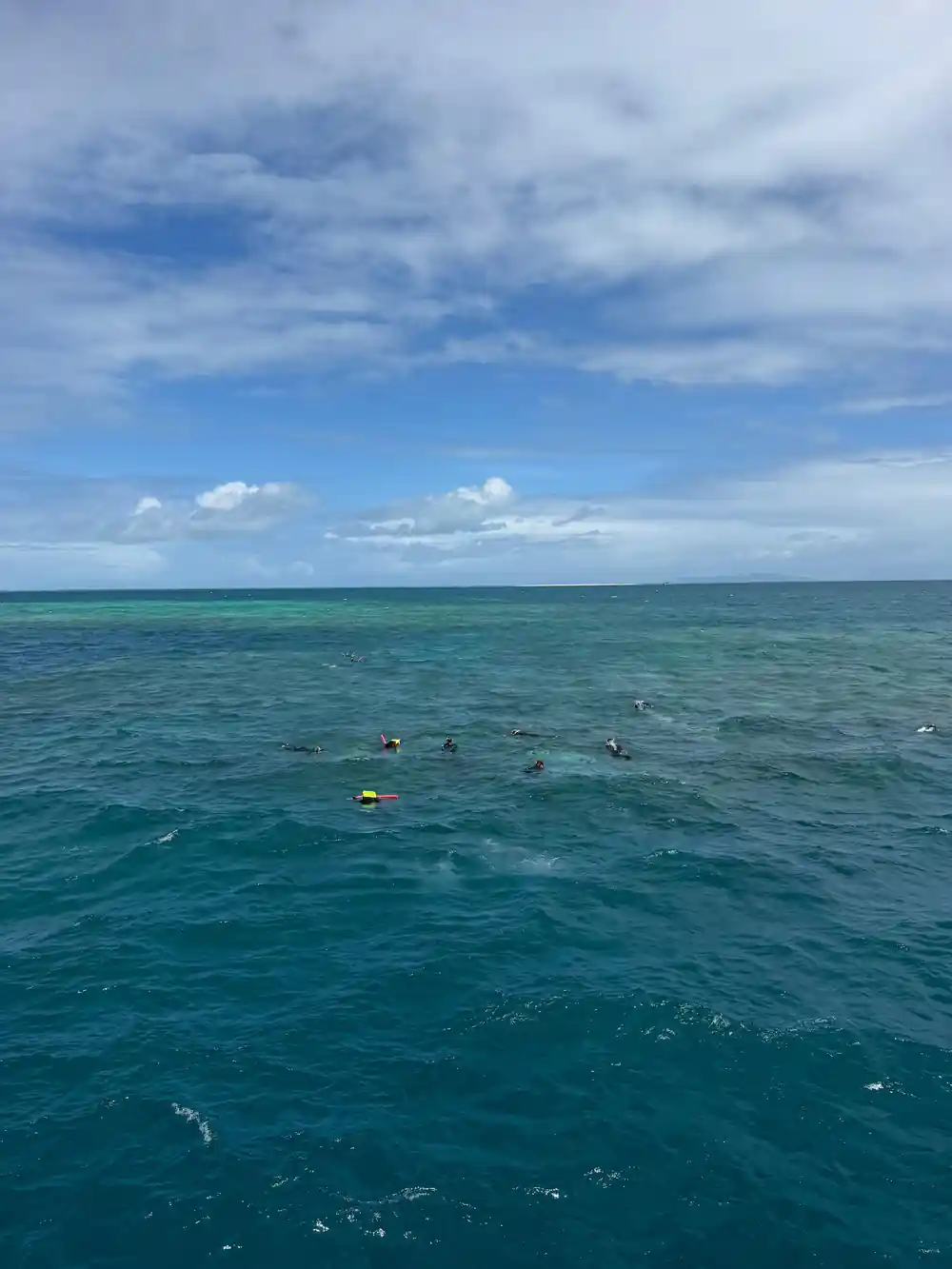 Snorkellers scattered across flat water above the reef
