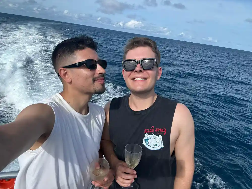 Two guests with drinks on the open deck at sea